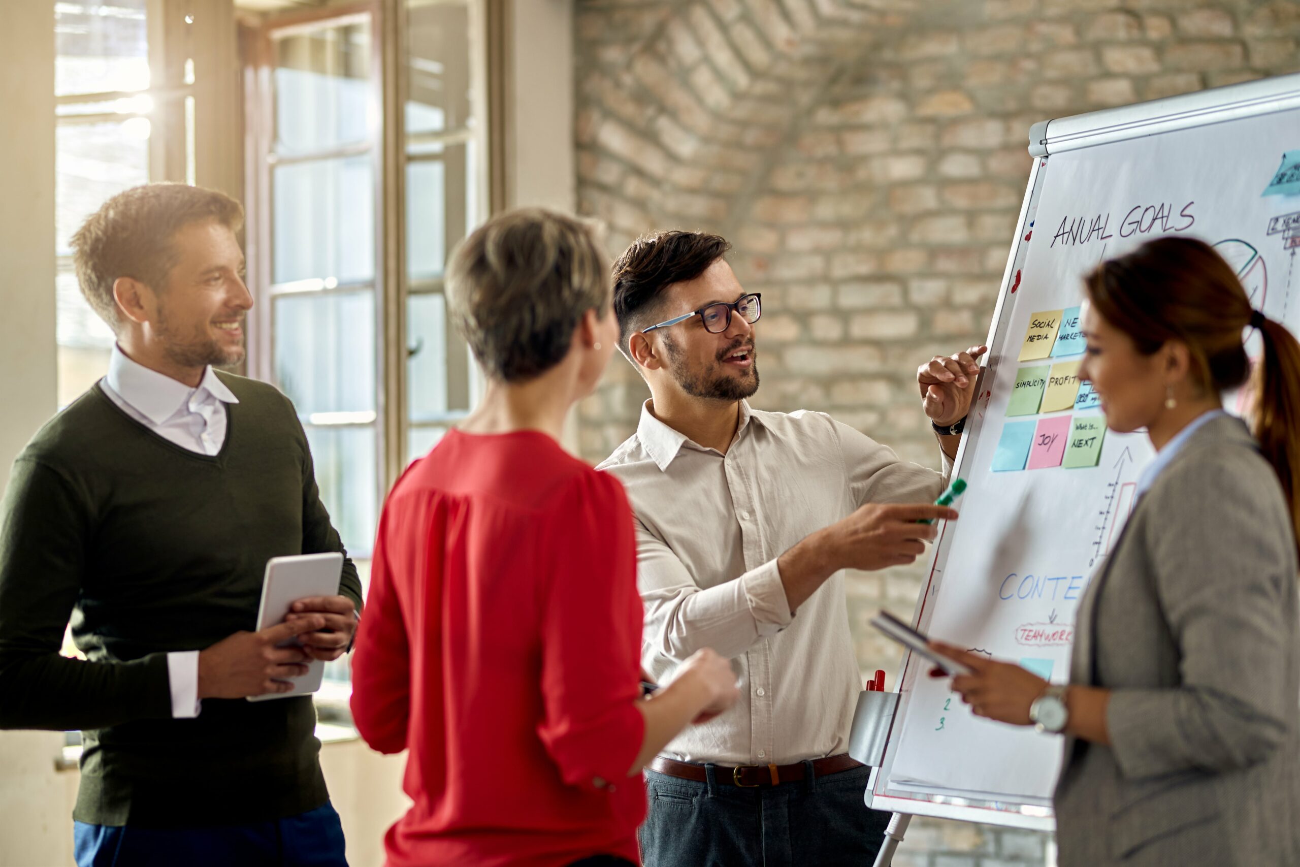 business-team-cooperating-while-developing-new-business-strategy-office-focus-is-young-man-presenting-ideas-whiteboard-min